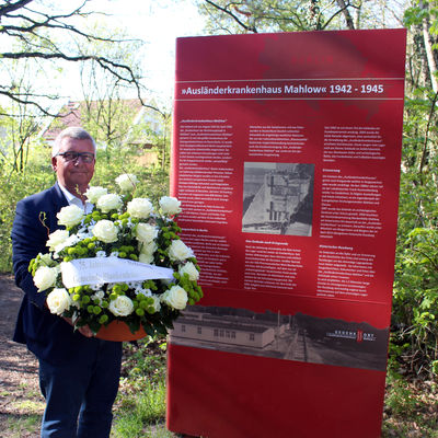 Bürgermeister Michael Schwuchow legt ein Blumengesteck am Ausländerkrankenhaus nieder